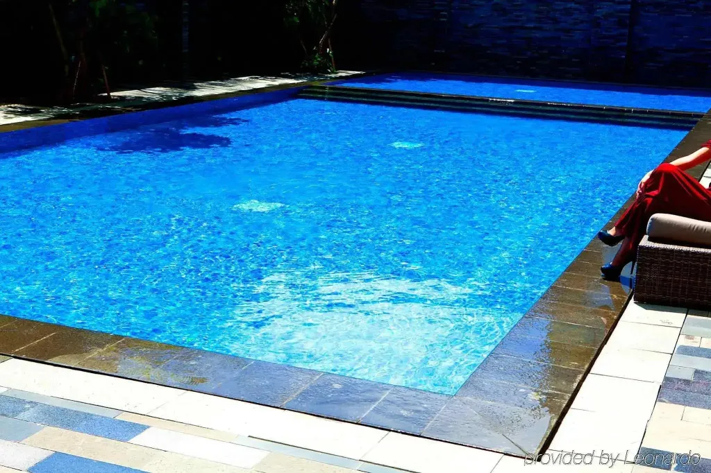 Une piscine rectangulaire aux eaux turquoise bordée d'une terrasse carrelée.