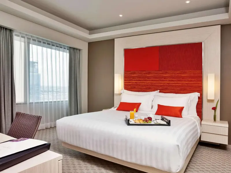Une chambre lumineuse avec un grand lit et un plateau de petit-déjeuner.