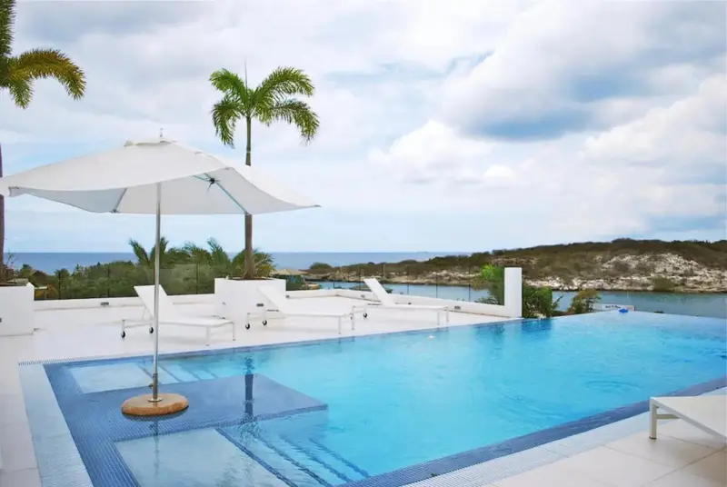 Une piscine à débordement surplombe la mer et une côte rocheuse.