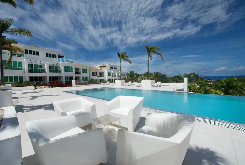 Espace détente avec mobilier blanc au bord d'une piscine à débordement.