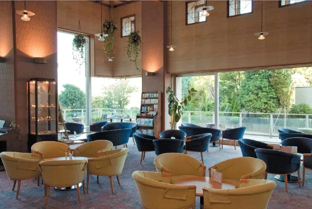 Espace de détente intérieur avec tables basses et fauteuils colorés près de grandes baies vitrées.