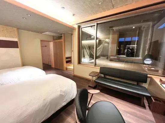 Une chambre lumineuse avec deux lits et une grande fenêtre donnant sur un espace intérieur.