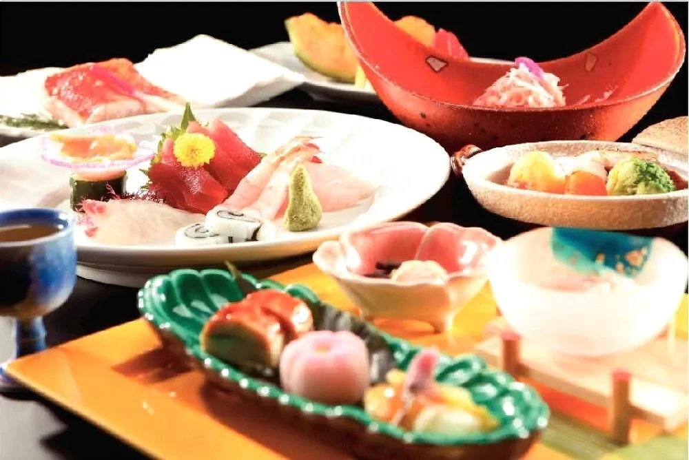 Assortiment de plats de fruits de mer et de légumes présentés dans de la vaisselle colorée.