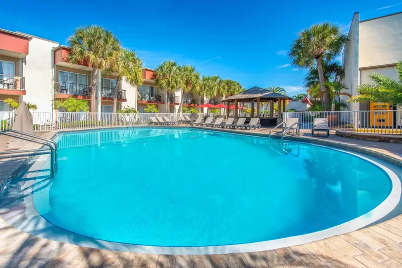 Une piscine rectangulaire avec des transats et des parasols sous un abri.