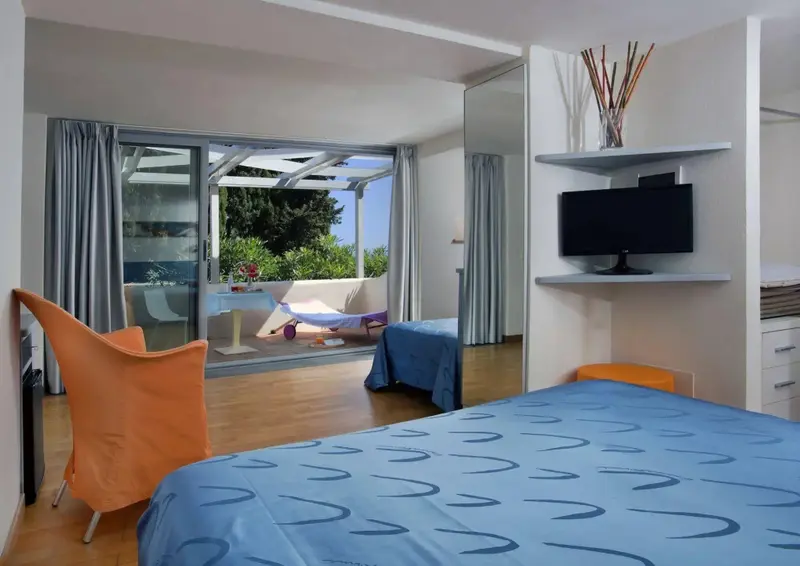 Une chambre lumineuse s'ouvre sur une terrasse ensoleillée.