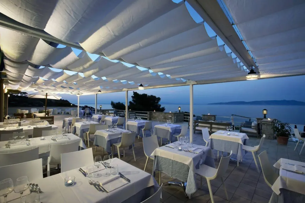 Une terrasse de restaurant couverte offre une vue sur la mer au coucher du soleil.