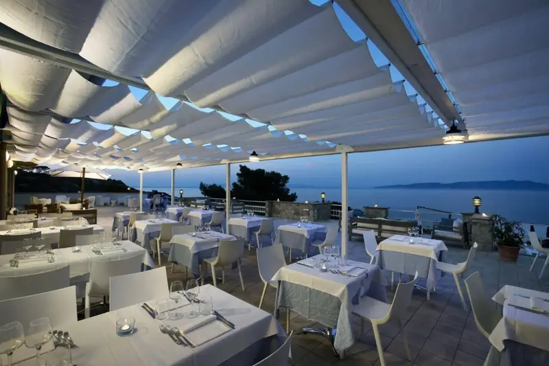 Une terrasse de restaurant couverte offre une vue sur la mer au coucher du soleil.