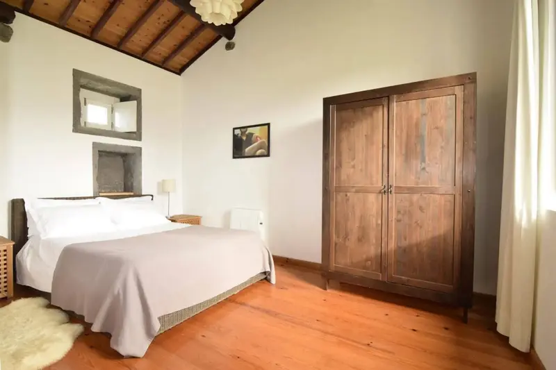 Une chambre lumineuse avec un grand lit et un placard en bois.