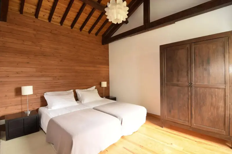 Une chambre lumineuse avec deux lits simples et un mur en bois.