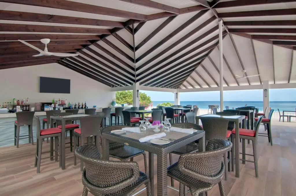 Une salle à manger ouverte sur la mer avec un bar en fond.
