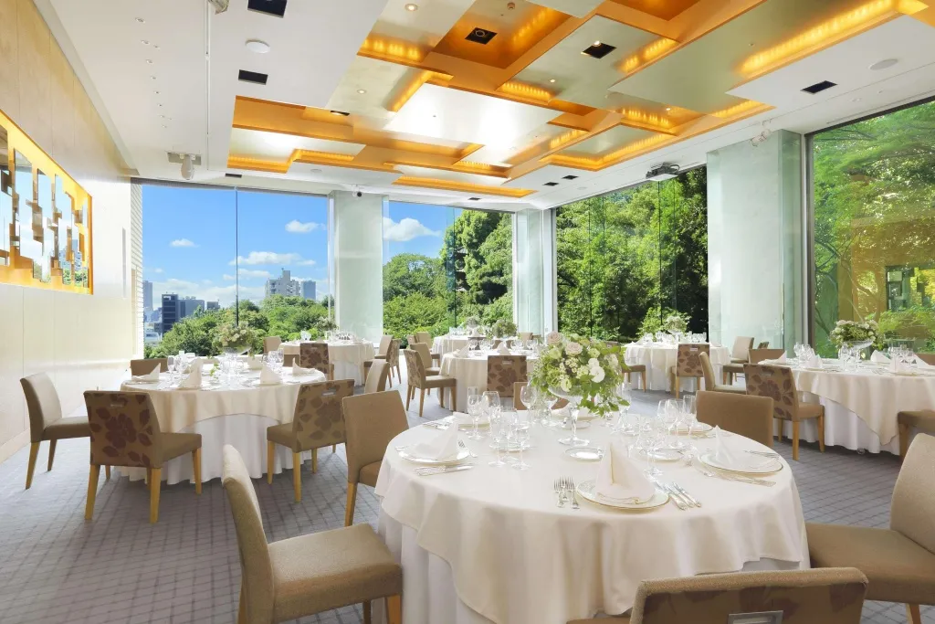 Une salle lumineuse avec des tables rondes dressées pour un repas.