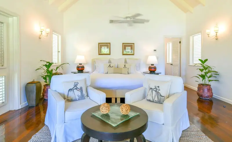 Une chambre lumineuse avec un grand lit et deux fauteuils confortables.