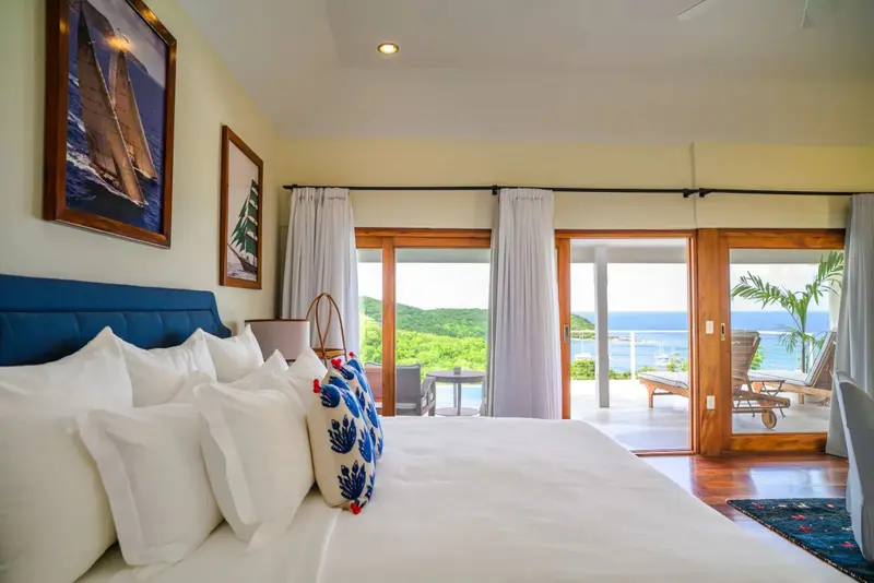 Une chambre lumineuse avec un grand lit donnant sur une vue sur la mer.