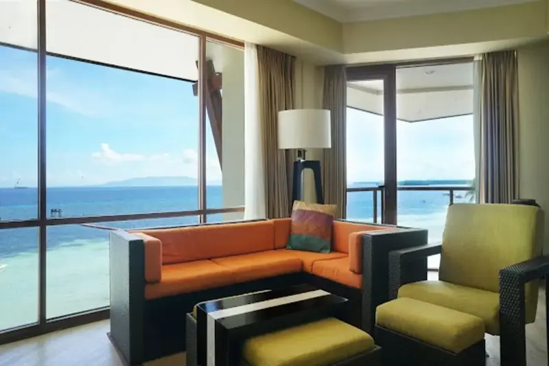 Un salon lumineux avec vue sur la mer à travers de grandes baies vitrées.