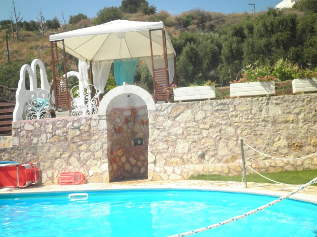 Une piscine avec un espace ombragé et une fontaine décorative.