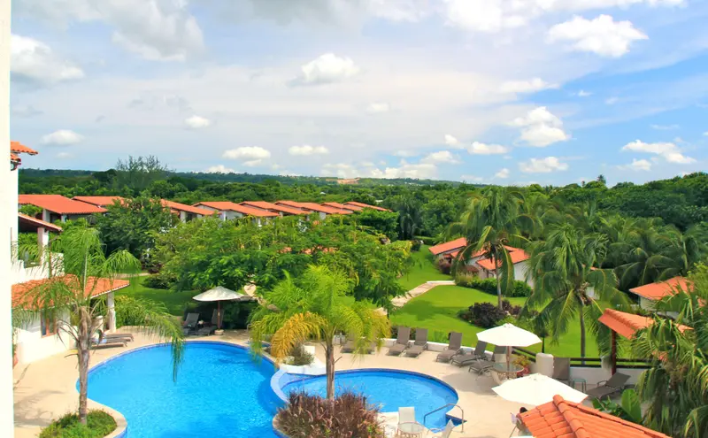 Vue aérienne d'un complexe hôtelier avec piscine et végétation luxuriante.