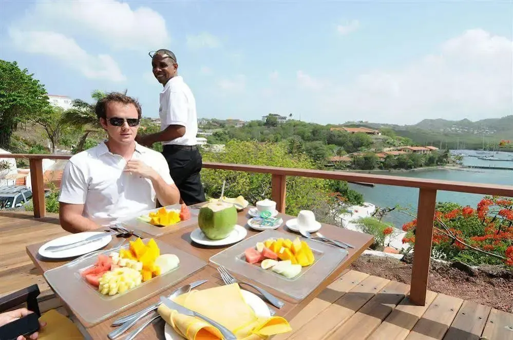 Un homme prend son petit-déjeuner sur une terrasse avec vue sur la mer.
