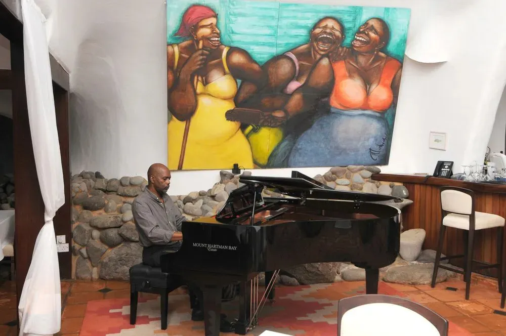 Un pianiste joue dans une salle décorée d'une grande peinture colorée.