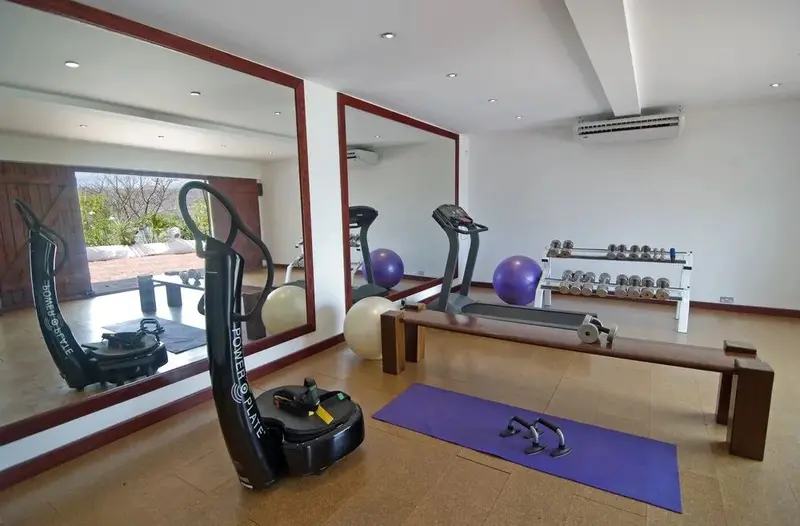 Une salle de sport lumineuse avec des équipements de fitness et des miroirs.