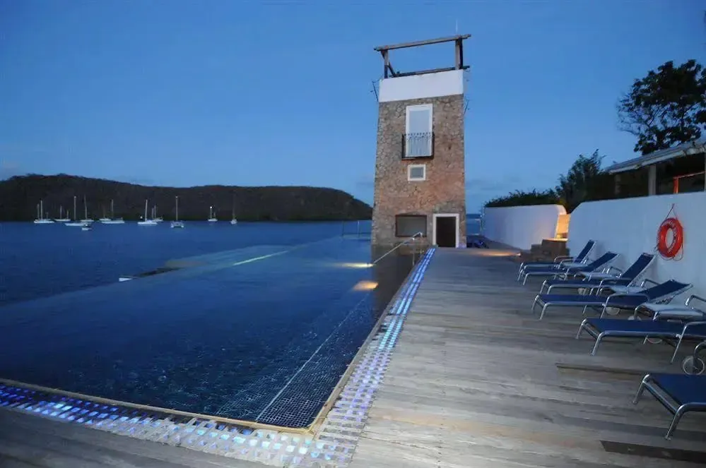 Terrasse avec transats et piscine à débordement donnant sur une baie.