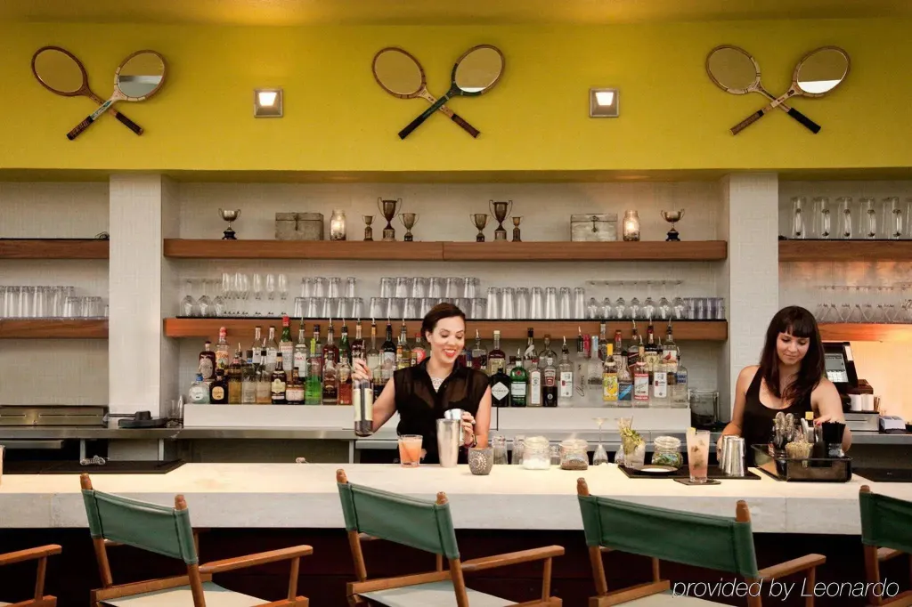 Un bar avec deux employées derrière le comptoir, des bouteilles et des verres.