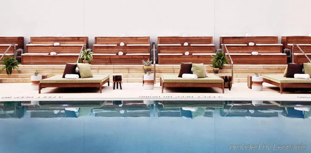 Transats et plantes ornent le bord d'une piscine rectangulaire.