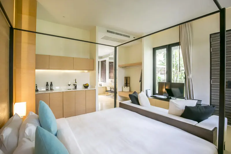 Une chambre lumineuse avec un lit et une kitchenette.