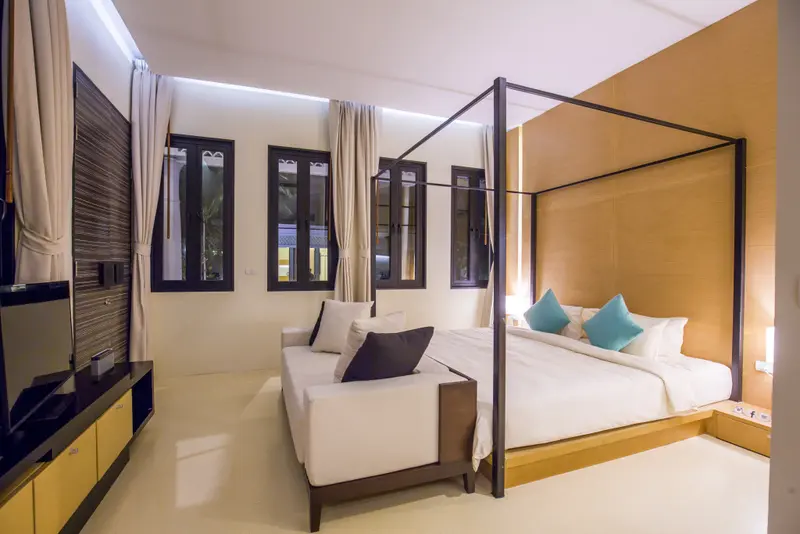 Une chambre lumineuse avec un grand lit à baldaquin et un coin salon.