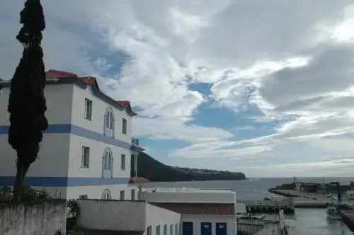 Bâtiment blanc et bleu avec un toit rouge surplombant un port.