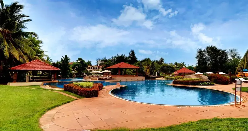 Piscine extérieure avec parasols et végétation luxuriante.