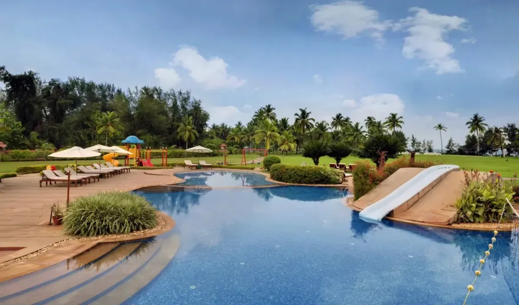 Une piscine avec un toboggan et des transats sous des parasols.