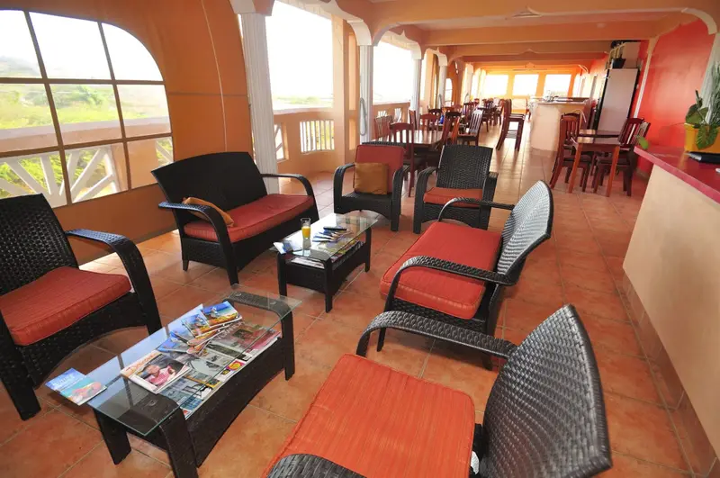 Espace de détente avec mobilier en rotin et vue sur un paysage verdoyant.