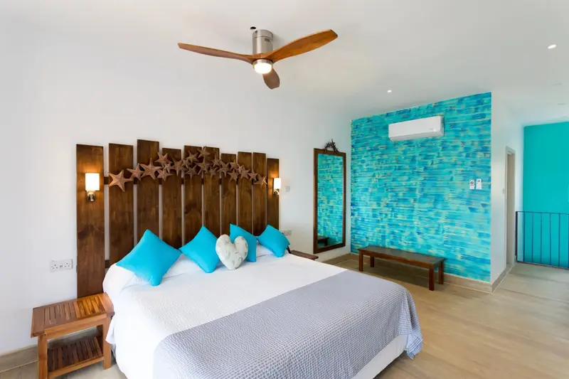 Une chambre lumineuse avec un grand lit et un décor mural bleu.