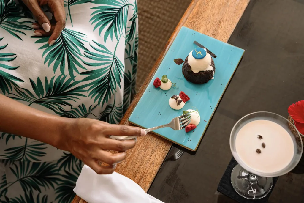 Une personne déguste un dessert sur une table en bois.