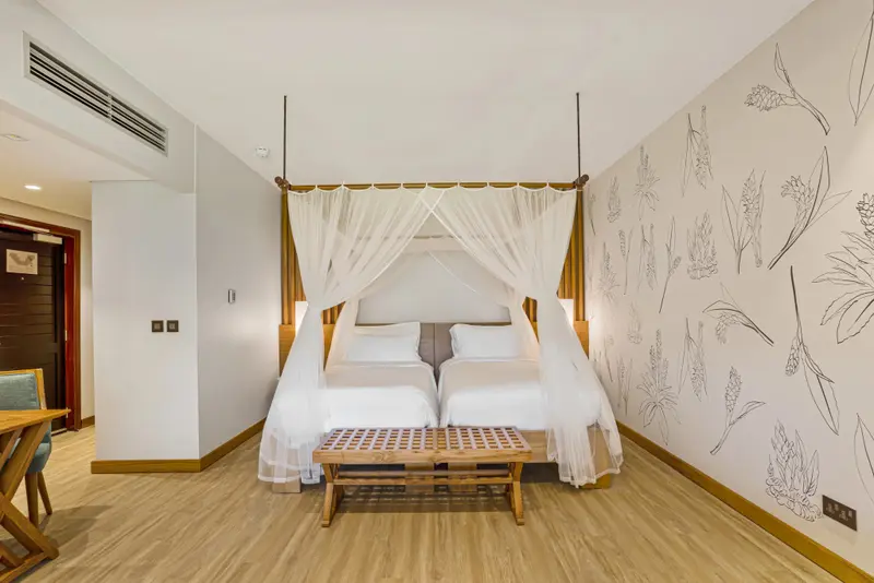 Une chambre lumineuse avec un grand lit à baldaquin et un décor floral sur les murs.