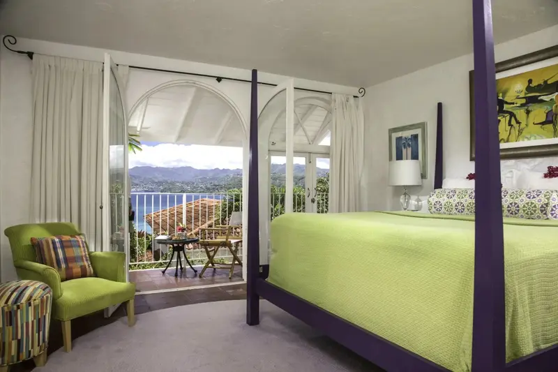 Une chambre lumineuse avec un lit à baldaquin et une vue sur la mer.