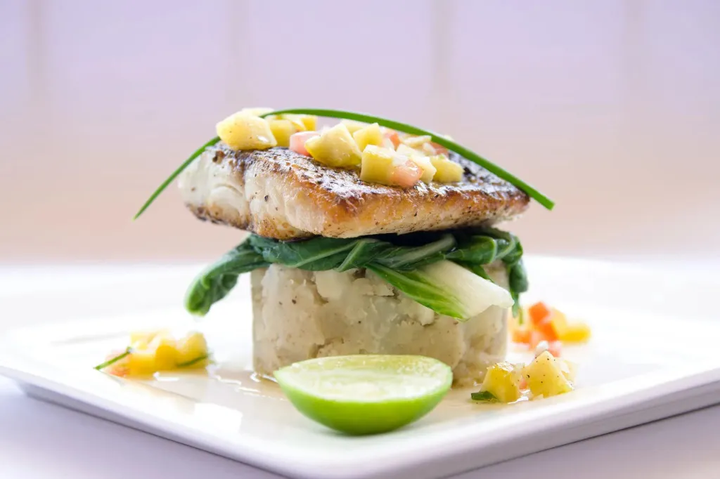 Un plat de poisson grillé est présenté sur une assiette blanche.