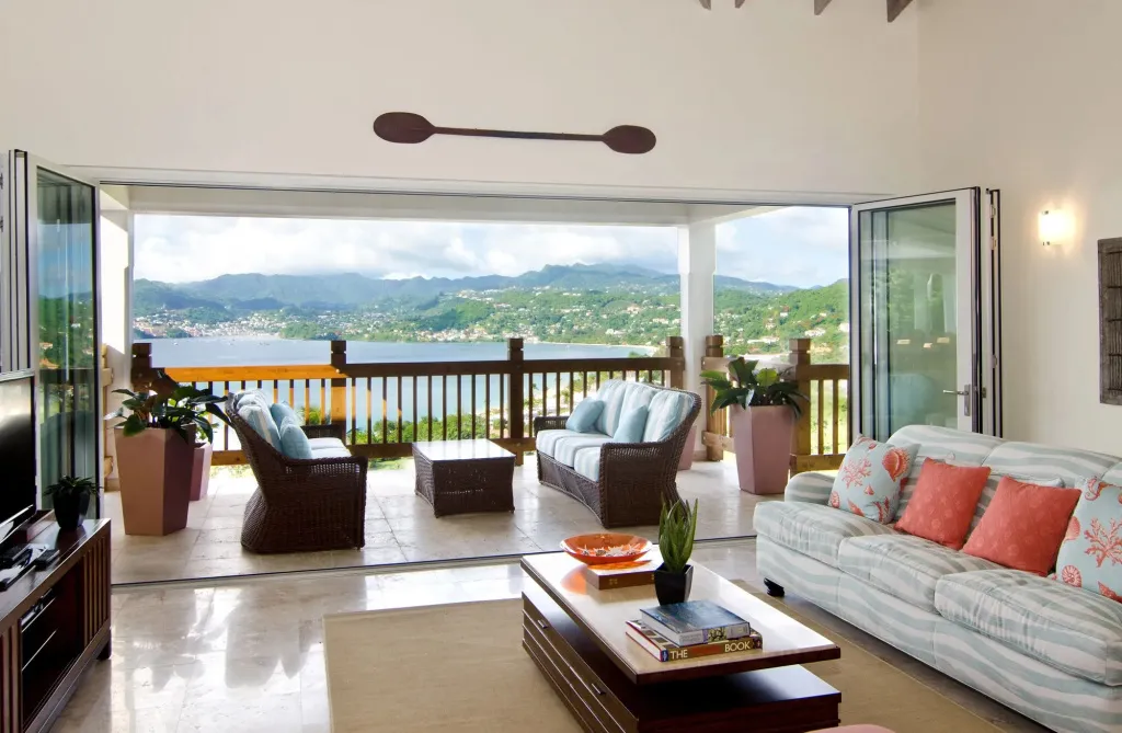 Un salon lumineux s'ouvre sur une terrasse avec vue sur la mer et les montagnes.