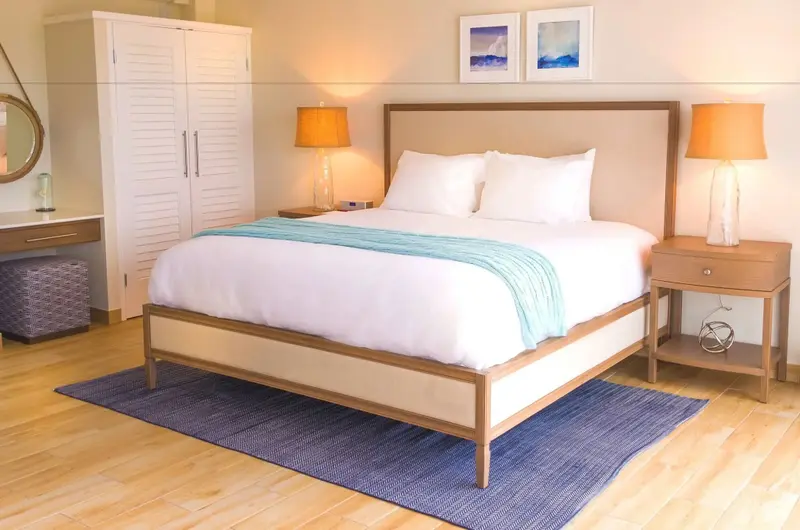 Une chambre lumineuse avec un grand lit recouvert d'une courtepointe turquoise.