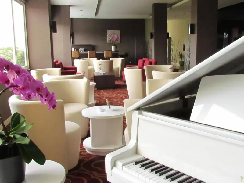 Un espace de détente intérieur avec des fauteuils et un piano à queue.