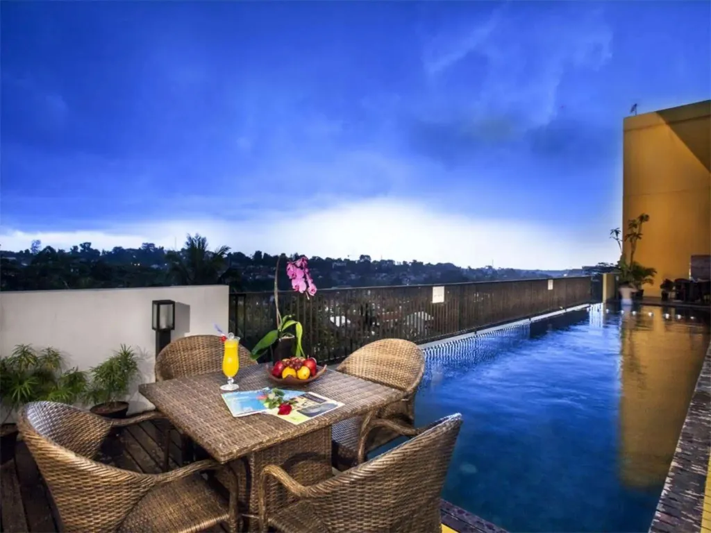 Une table de repas est mise en scène sur une terrasse avec une piscine à débordement et une vue sur un paysage vallonné.