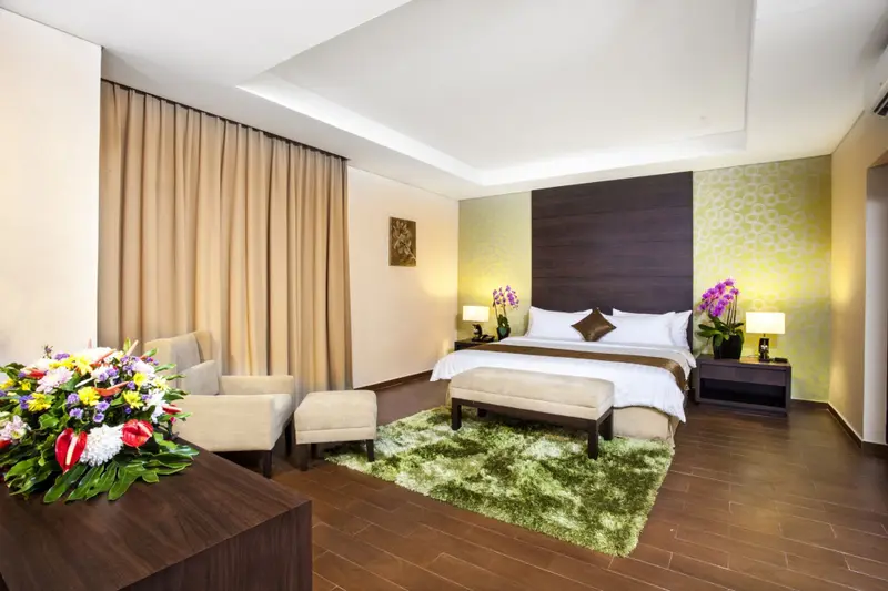 Une chambre lumineuse avec un lit double et un coin salon.