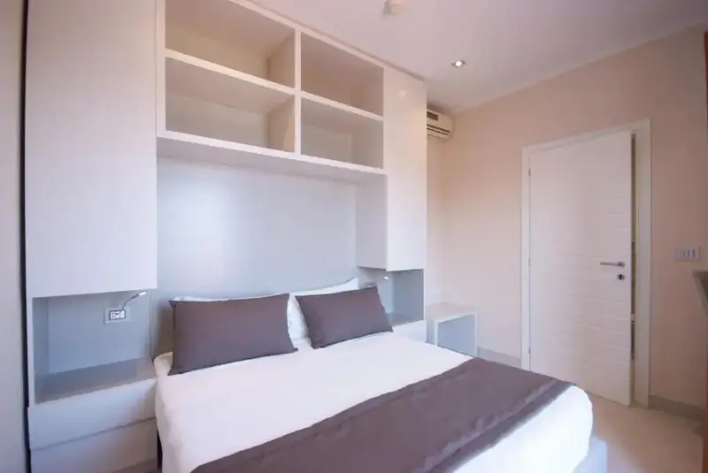 Une chambre à coucher lumineuse avec un grand lit et des rangements intégrés.