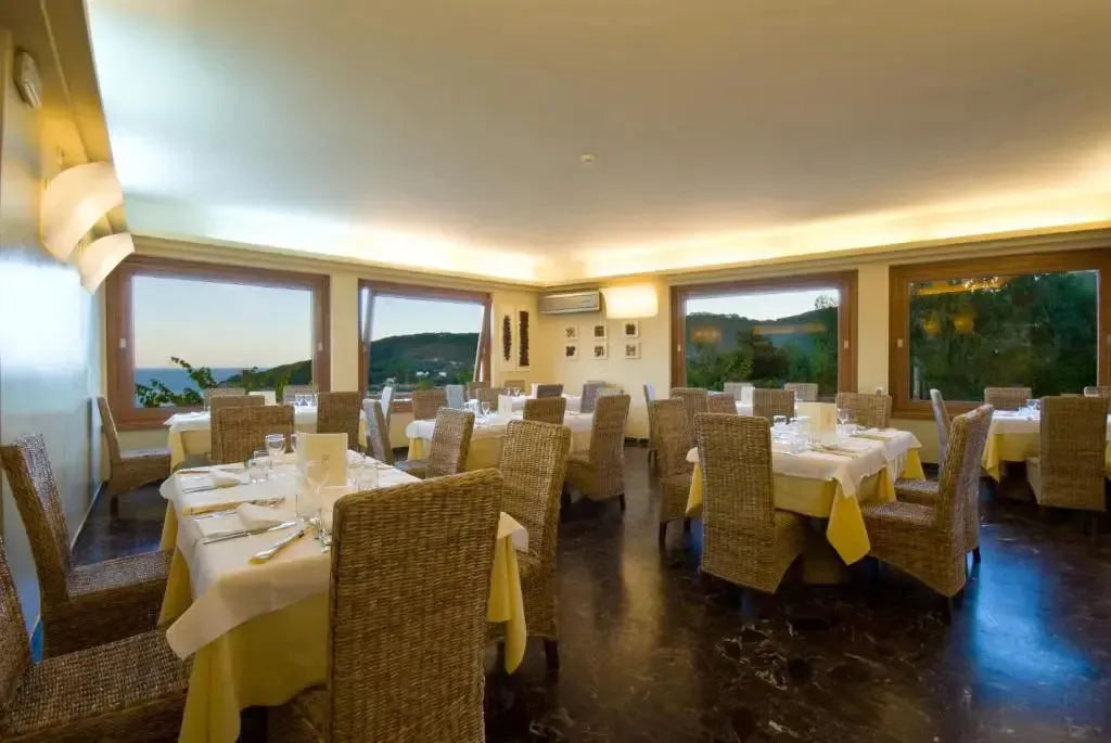 Une salle lumineuse avec des tables dressées face à une vue sur la mer.