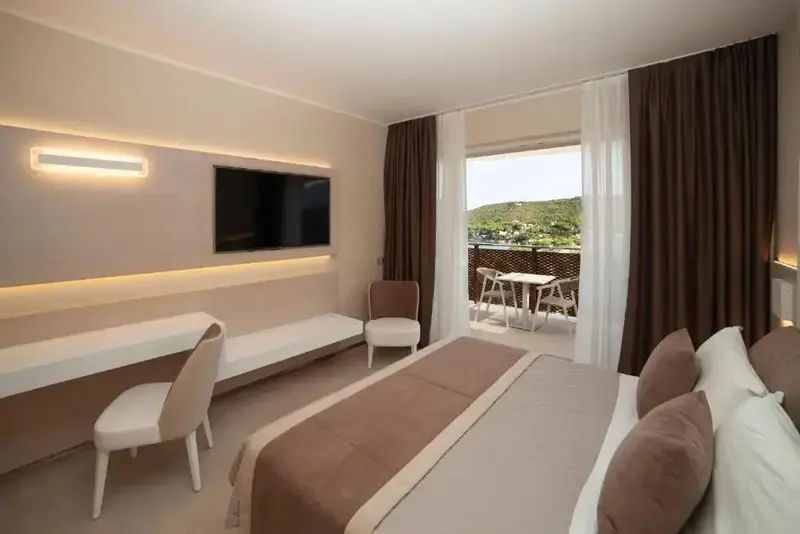 Une chambre lumineuse s'ouvre sur une terrasse avec vue sur la végétation.