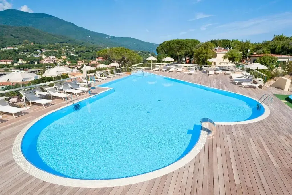 Une piscine rectangulaire avec des transats et des parasols en bord.