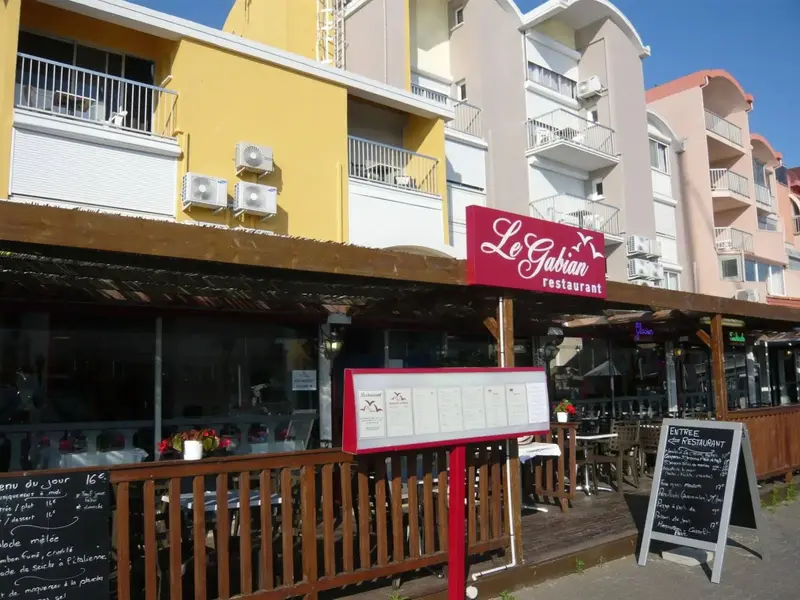 Façade d'un restaurant avec une terrasse ensoleillée et des menus exposés.