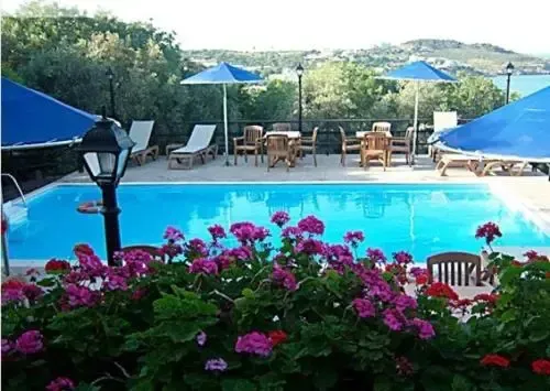 Une piscine bordée de chaises longues et de tables, entourée de végétation fleurie.