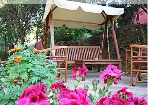 Un espace de détente ombragé avec des bancs en bois et des fleurs colorées.