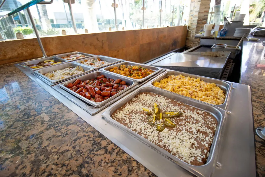 Un buffet propose une variété de plats chauds dans des bacs en acier inoxydable.
